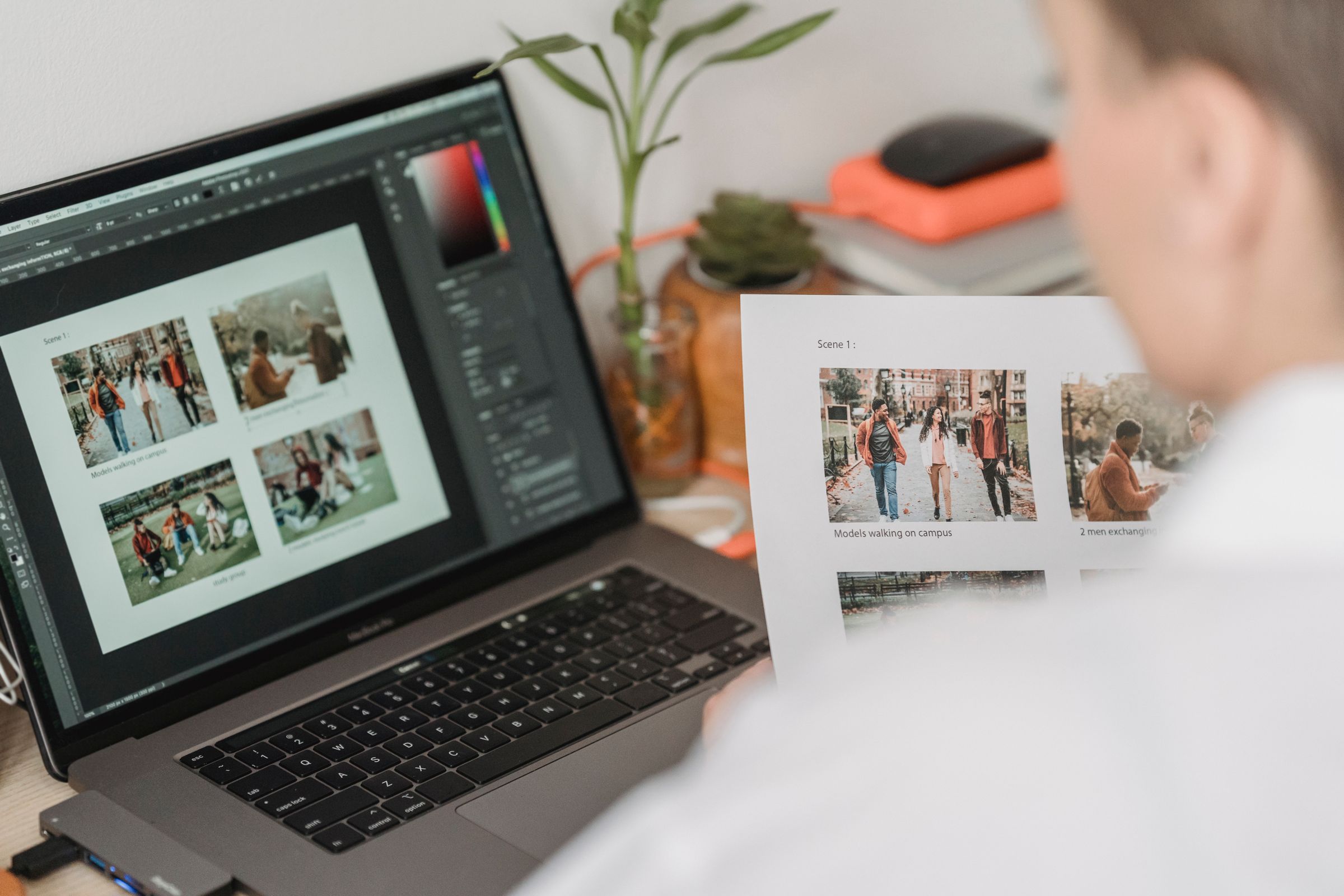 Designer arranging a page layout on screen with printed proofs